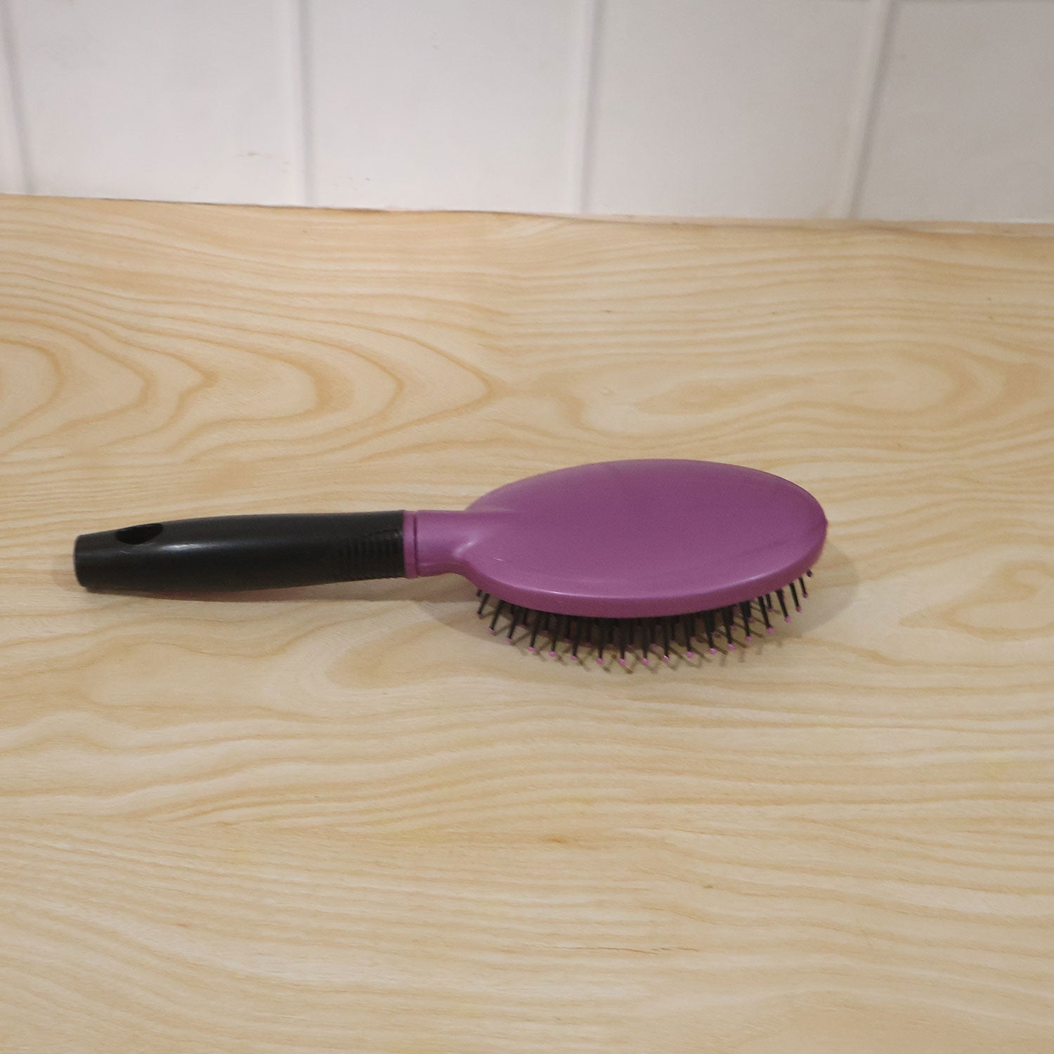 Person brushing hair with cushioned paddle brush for smooth styling