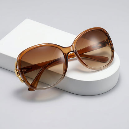 Close-up of gradient tinted lenses and gold floral accent on oversized women's sunglasses.