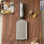 Stainless steel cheese grater with plastic handle for versatile kitchen use