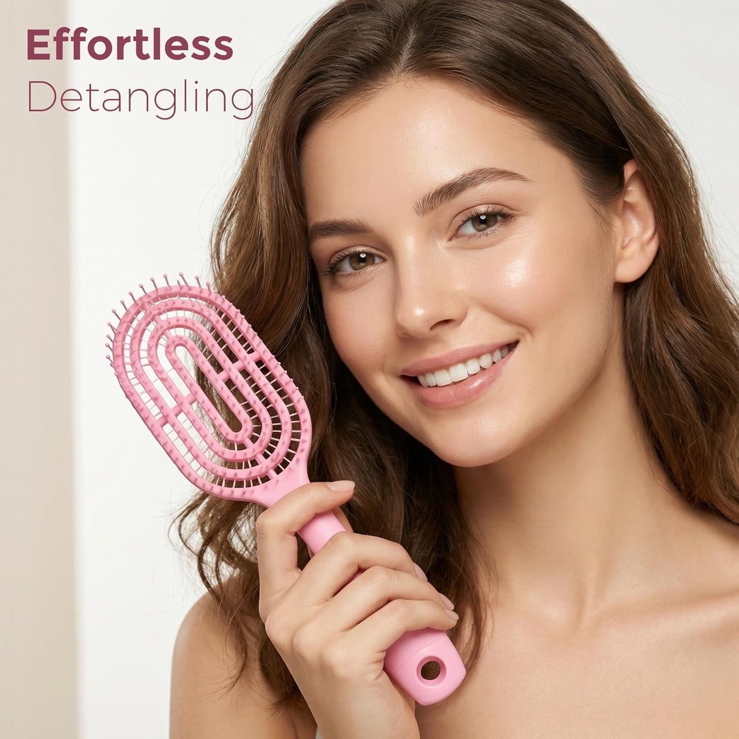 Person holding pink curved vented detangling hair brush while styling
