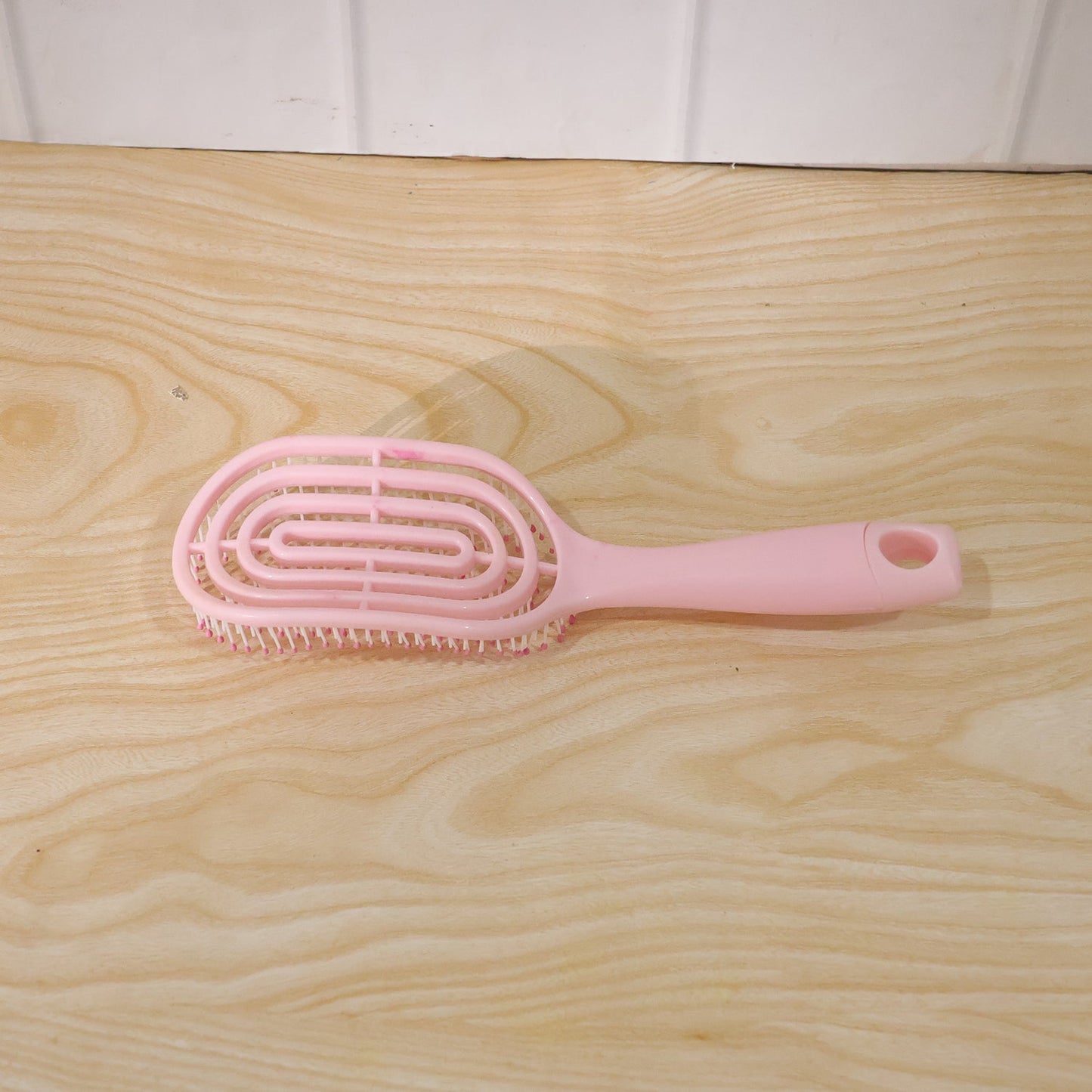 Woman brushing her hair with pink curved styling brush
